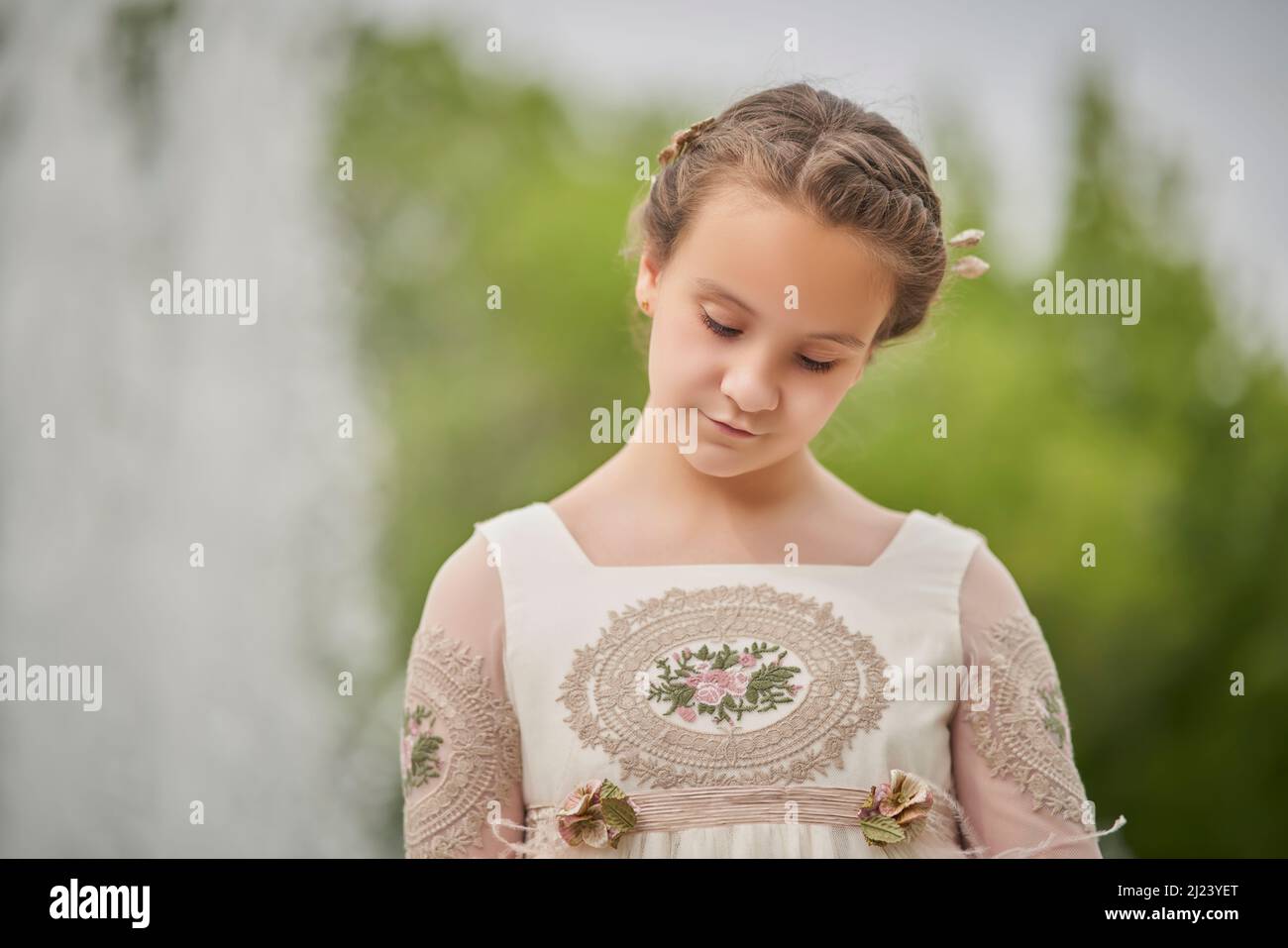 Communion girl posing in front of a fountain in a park Stock Photo
