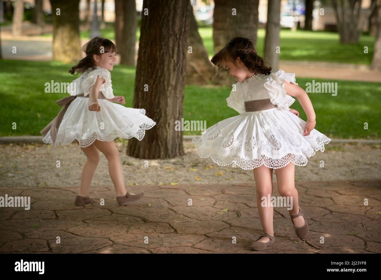 Communion girl twins dancing in a park Stock Photo