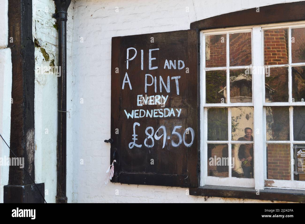 A cheeky pub food sign reflecting rising cost of living; at the Olde George, Shoreham, Kent, UK now being renovated. Close to the Mount Vineyard. Stock Photo