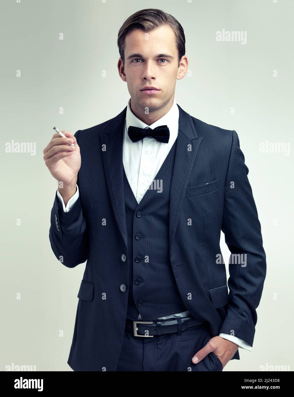 Suave and sophisticated. A studio portrait of a confident young gentleman smoking a cigarette. Stock Photo