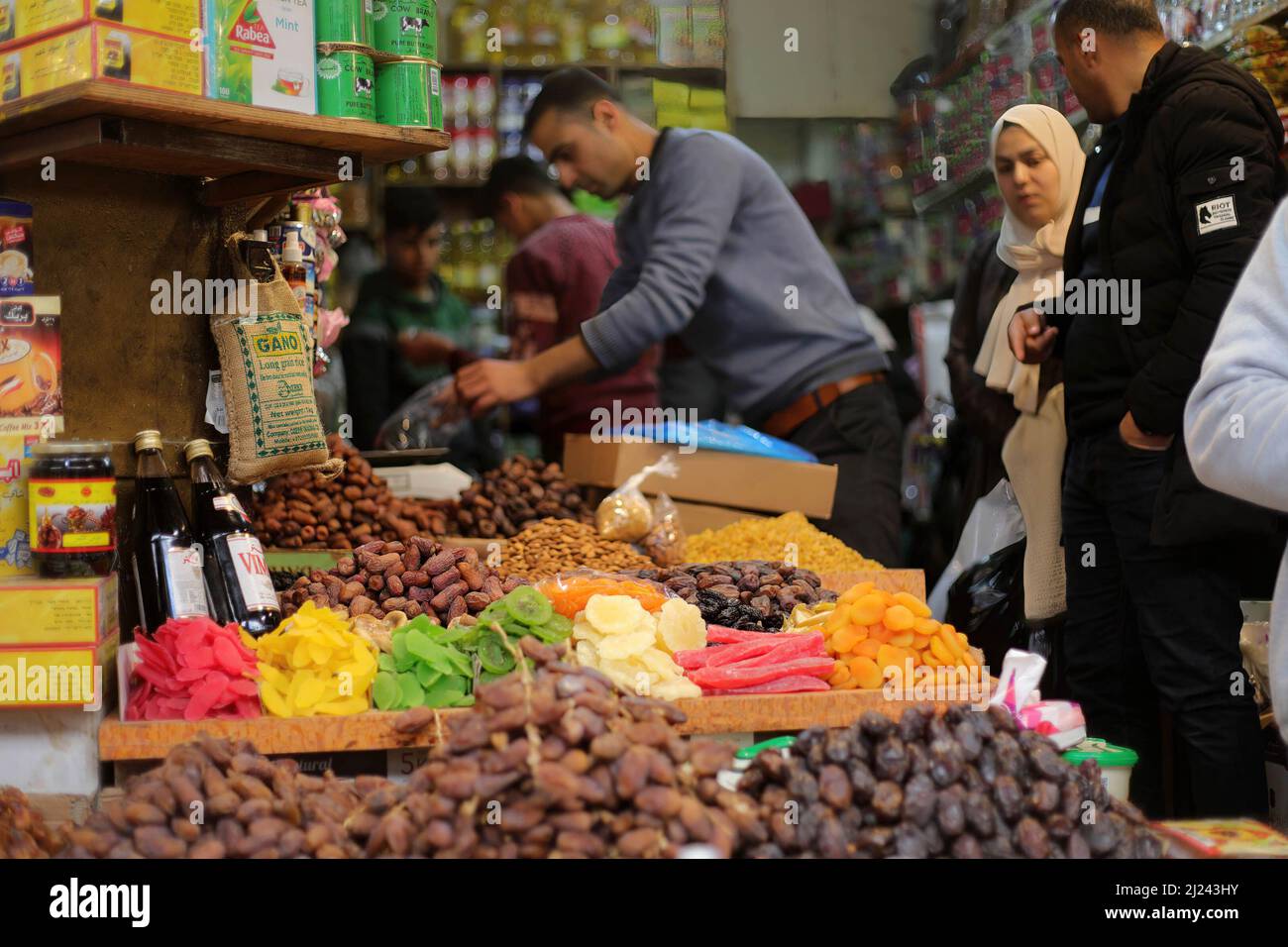 A Palestinian vendor sells dried fruit in his own shop in the oldest popular market called Al-Zawya in Gaza City. Palestinians prepare themselves ahead of the holy month of Ramadan by shopping in the oldest popular market called Al-Zawya middle of Gaza City, despite the high price of the goods in general caused by the Russian invasion of Ukraine. Muslims fast in Ramadan month, which is considered one of the pillars of Islam, in which Muslims abstain from eating and drinking until sunset. Stock Photo