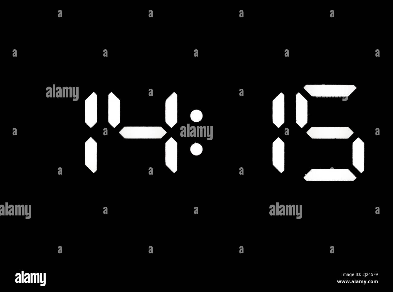 Real white led digital clock on a black background showing time 14:15 Stock Photo