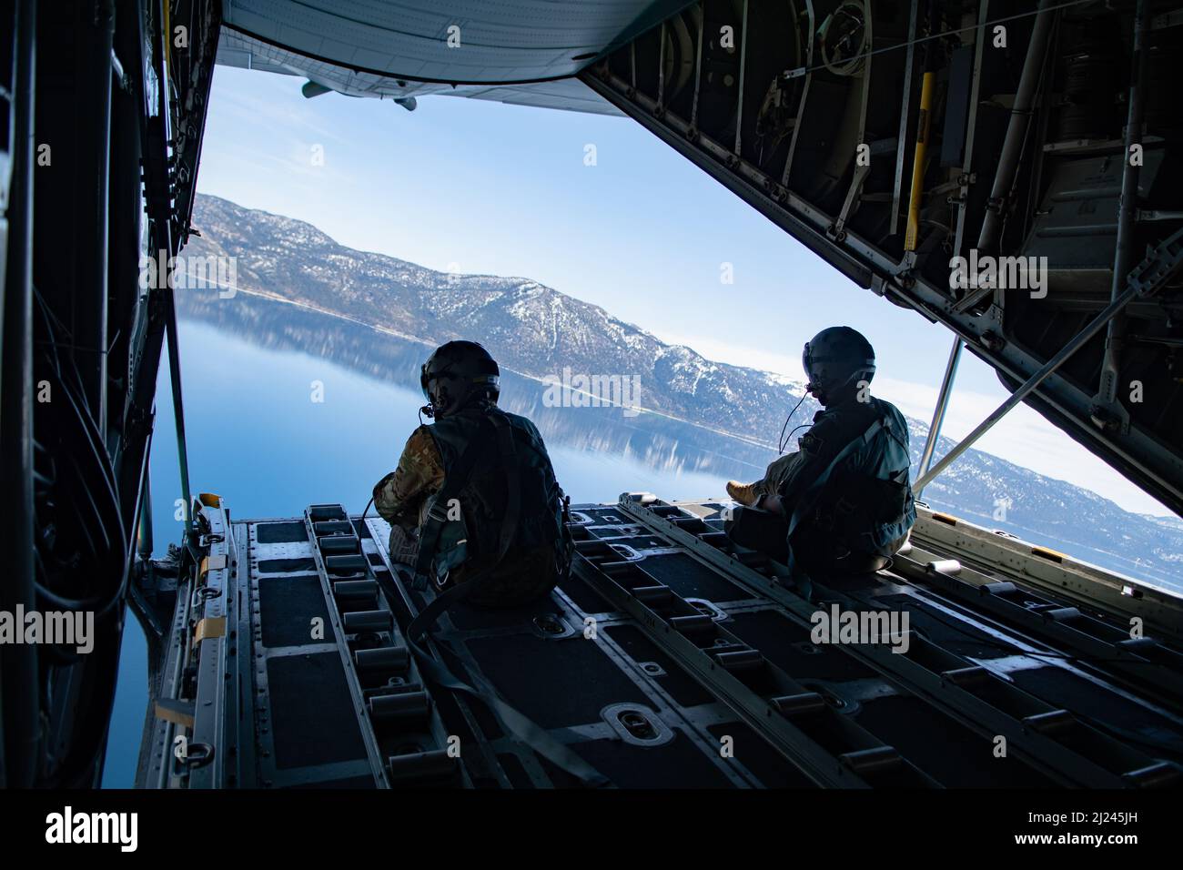 U.S. Air Force Staff Sgt. Sydney Goddard (left) and Airman First Class Jaylin Ford (right), Nevada Air National Guard loadmasters, sit on the ramp of a C-130 Hercules over Lake Tahoe during a civic leader orientation flight, March 25, 2022. Local civic leaders were brought on an orientation flight to increase their awareness about the Nevada Air National Guard and to help them better understand the missions that the Airmen execute on a daily basis. (U.S. Air National Guard photo by Senior Airman Thomas Cox) Stock Photo