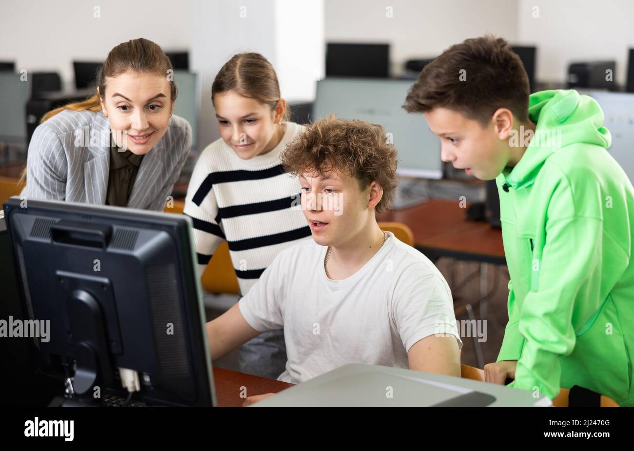 Female teacher helping schoolboy and schoo lgirl in computer class ...