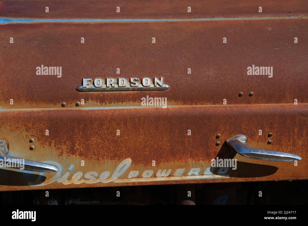metal,rivets,classic,oldRusting hood of  old Fordson Super Dexta tractor, full sun midday, rusty, with original decals. Stock Photo