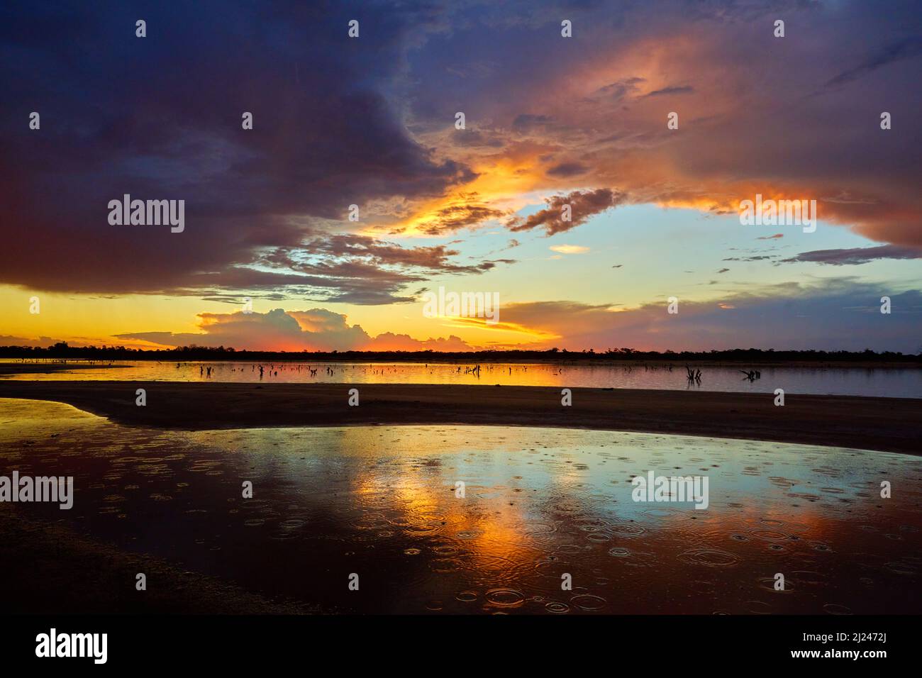 The end of a hot Summers day in far north western Victoria, with rain drops falling into a saline lake, with dramatic sunset forming the background. Stock Photo