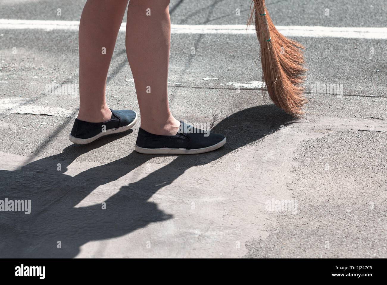 View of feet and broom . Woman sweeping the street Stock Photo Alamy