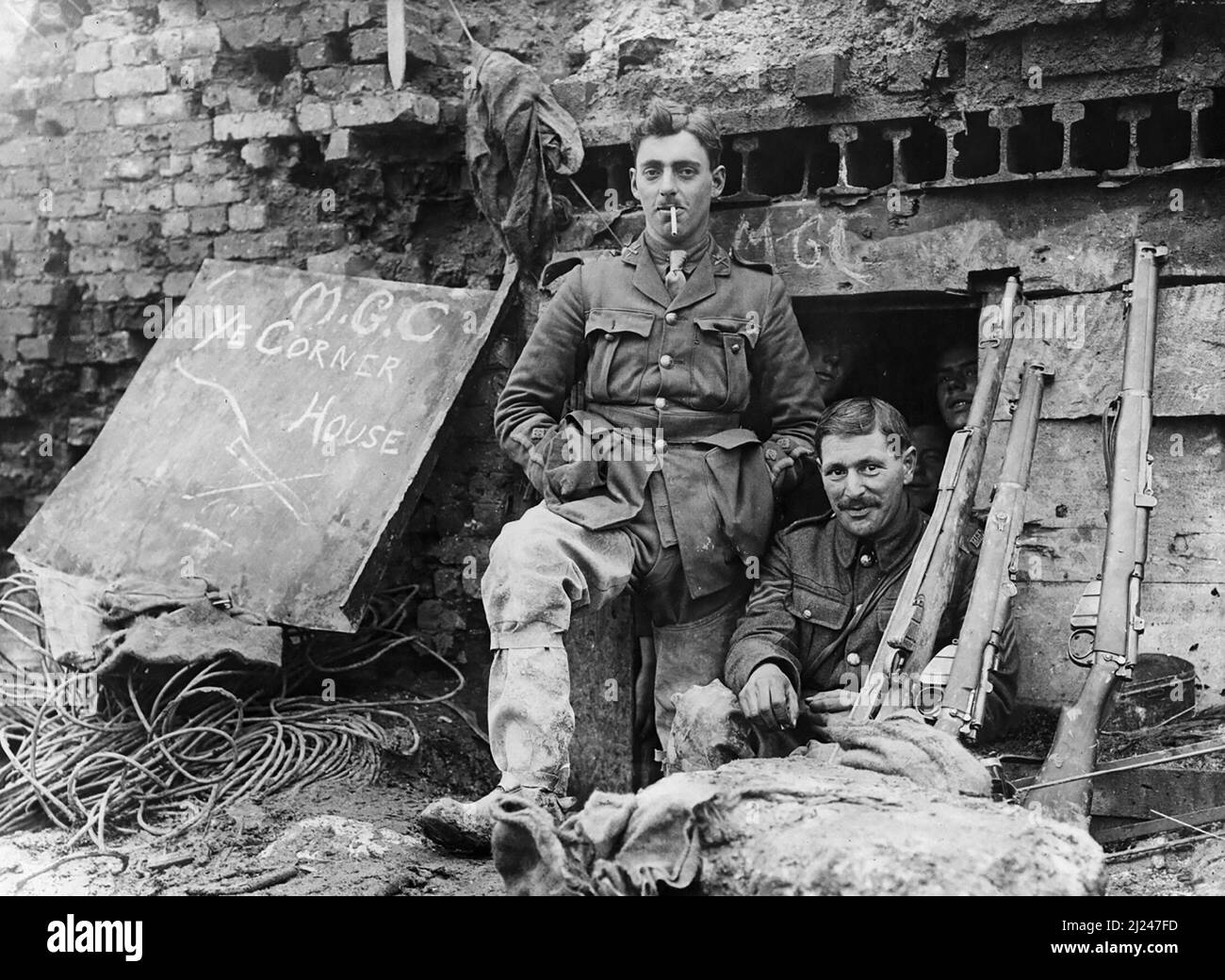 Machine Gun Corps officer, wearing trench waders, stands at the entrance of a captured German dug-out under the ruined Church at Beaumont Hamel, November, 1916. Dug-out nicknamed 'M.G.C. Ye Corner House'. Stock Photo