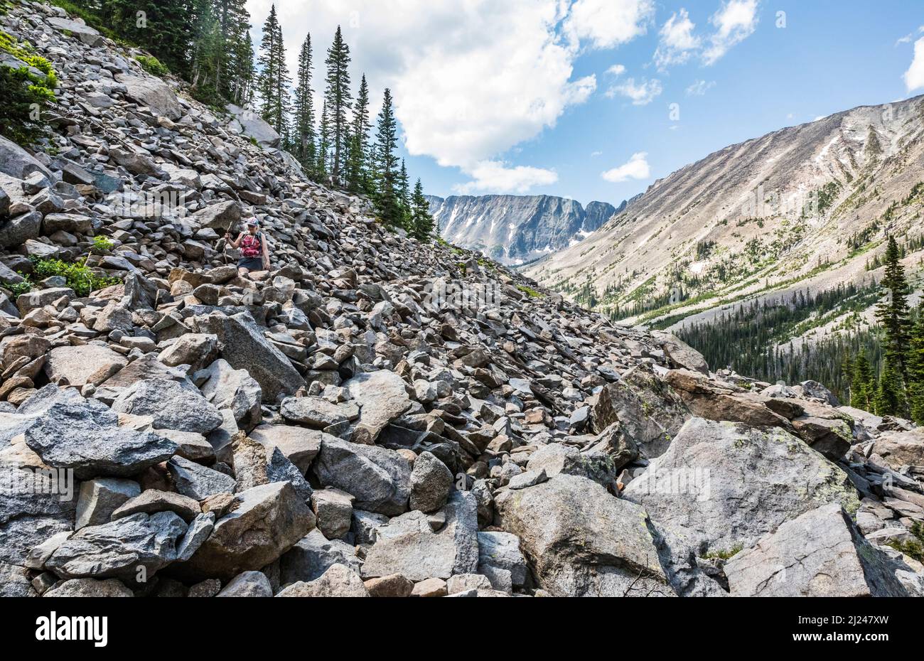 A woman hiking on a talus field in the mountains above Big Timber Creek trail on the way to Blue Lake in the Crazy Mountain range, Montana, USA. Stock Photo