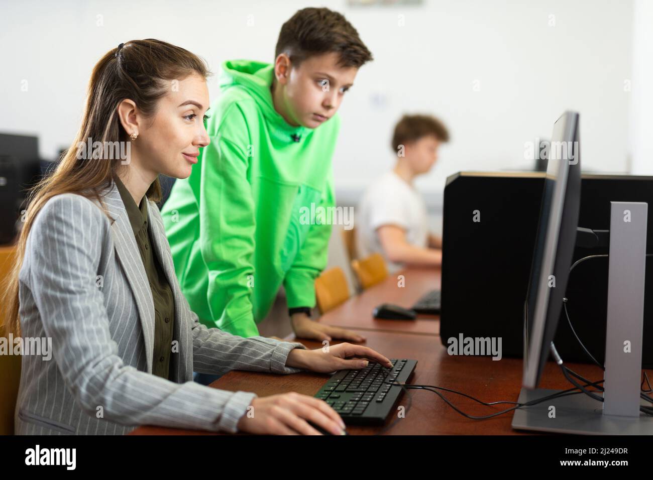Tween schoolboy helping young puzzled woman working with computer Stock ...