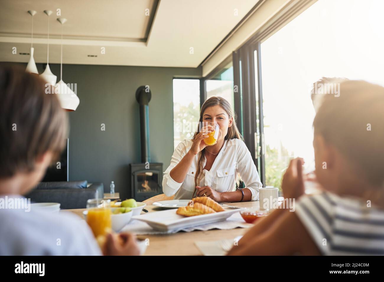 Mom loves listening to all their stories at breakfast. Shot of a mother having breakfast with her children at home. Stock Photo