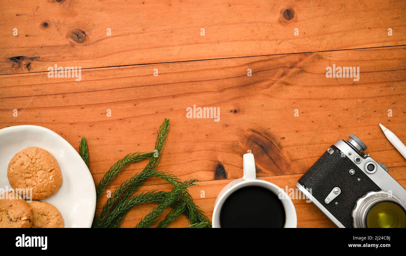 Overhead shot, A copy space for product display on wooden table background with camera, coffee cup, a plate of cookies and decor. Stock Photo