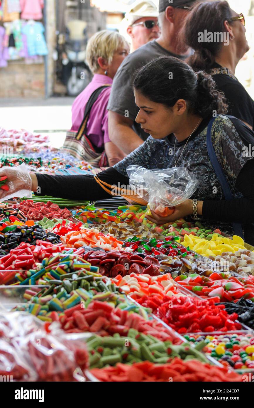 A woman selects colorful candies from a market vendor in Jerusalem, Israel. Stock Photo