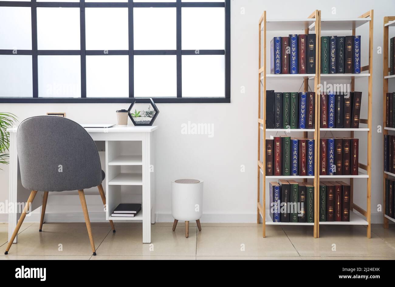 Stylish workplace and shelf unit with books in home library Stock Photo ...