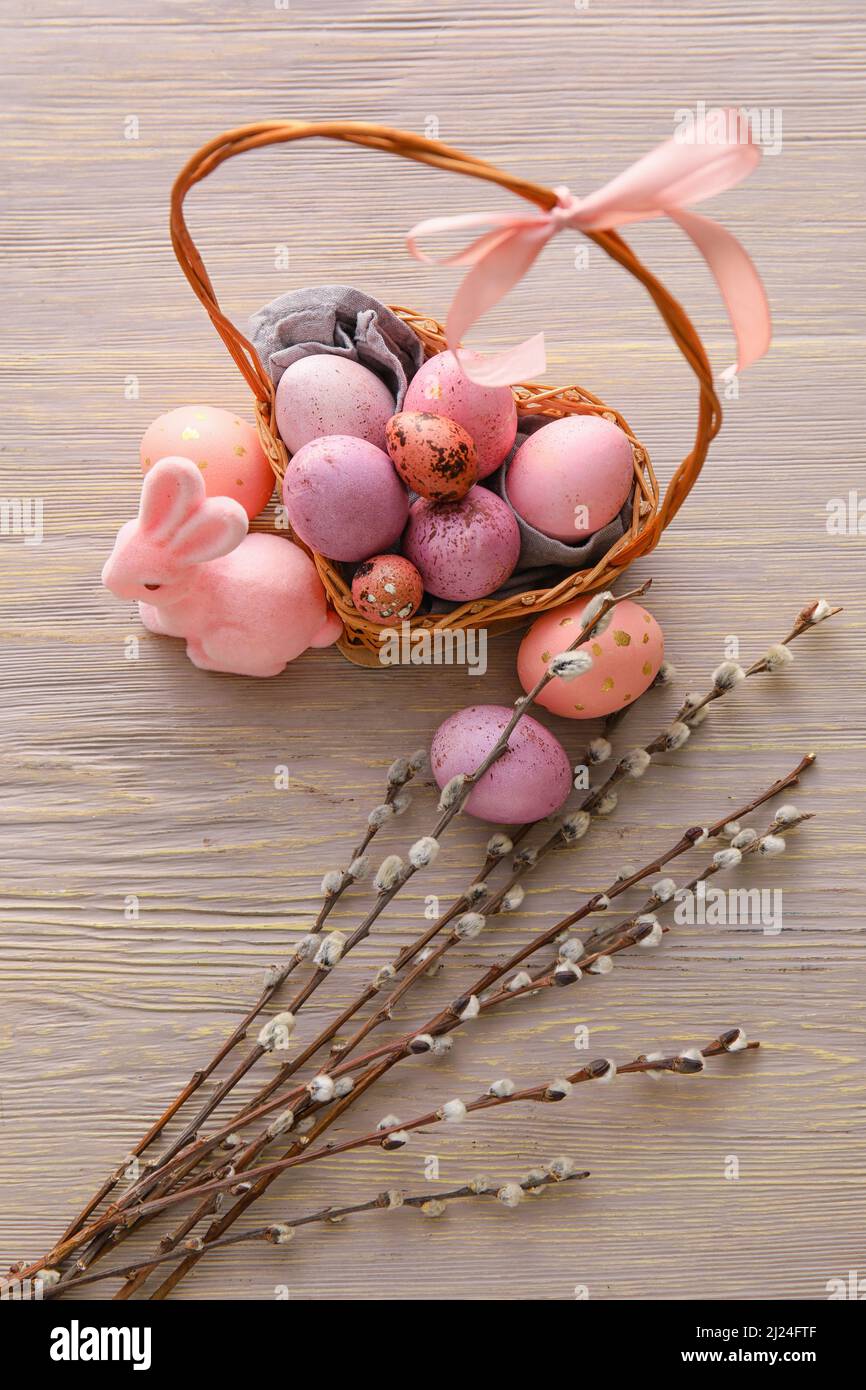 Basket with painted Easter eggs, willow branches and bunny on wooden ...
