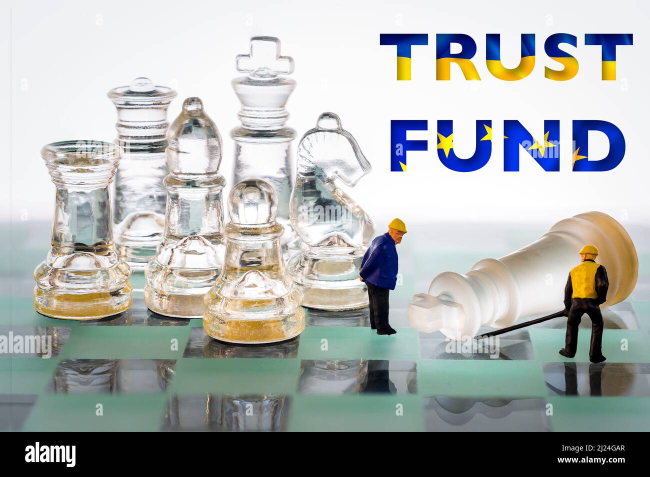 Trust Fund Europe and Ukraine flags colors letters. Fallen chess king miniature people workers helping. Stock Photo