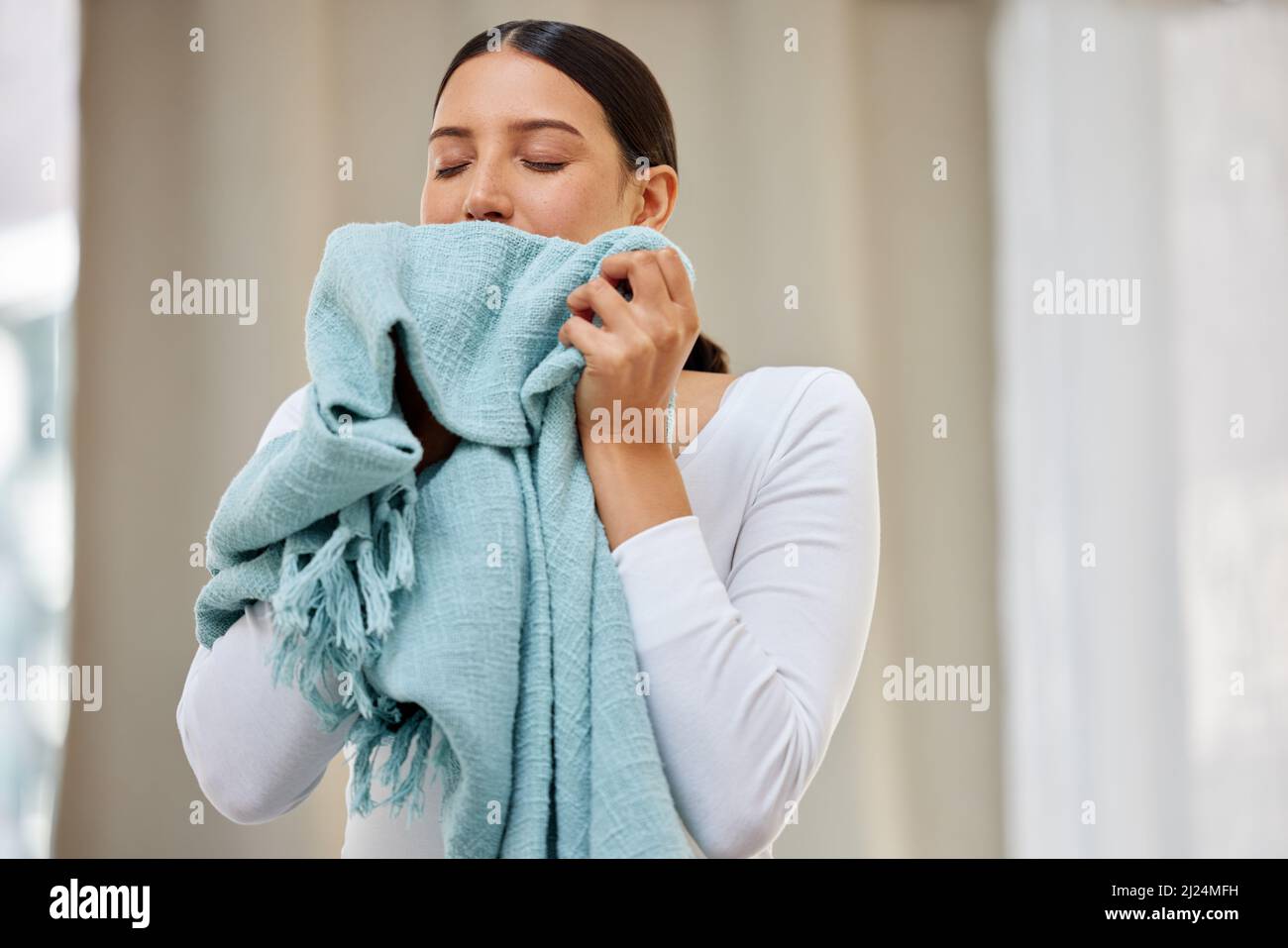 This smell should be bottled. Shot of a young woman smelling freshly cleaned laundry. Stock Photo