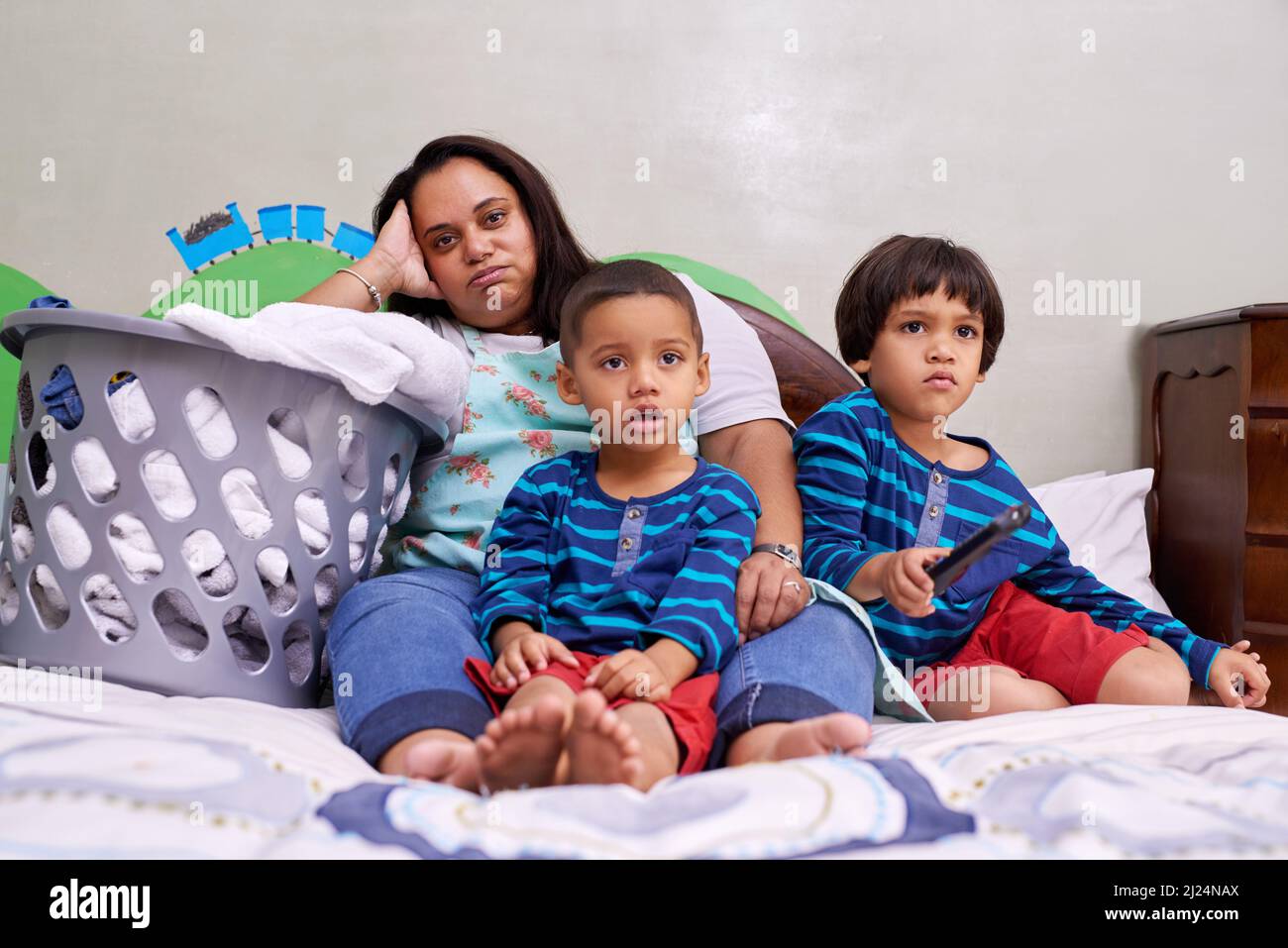 Theyre all just chilling out for a bit. Portrait of a mother sitting on a bed with her two sons. Stock Photo