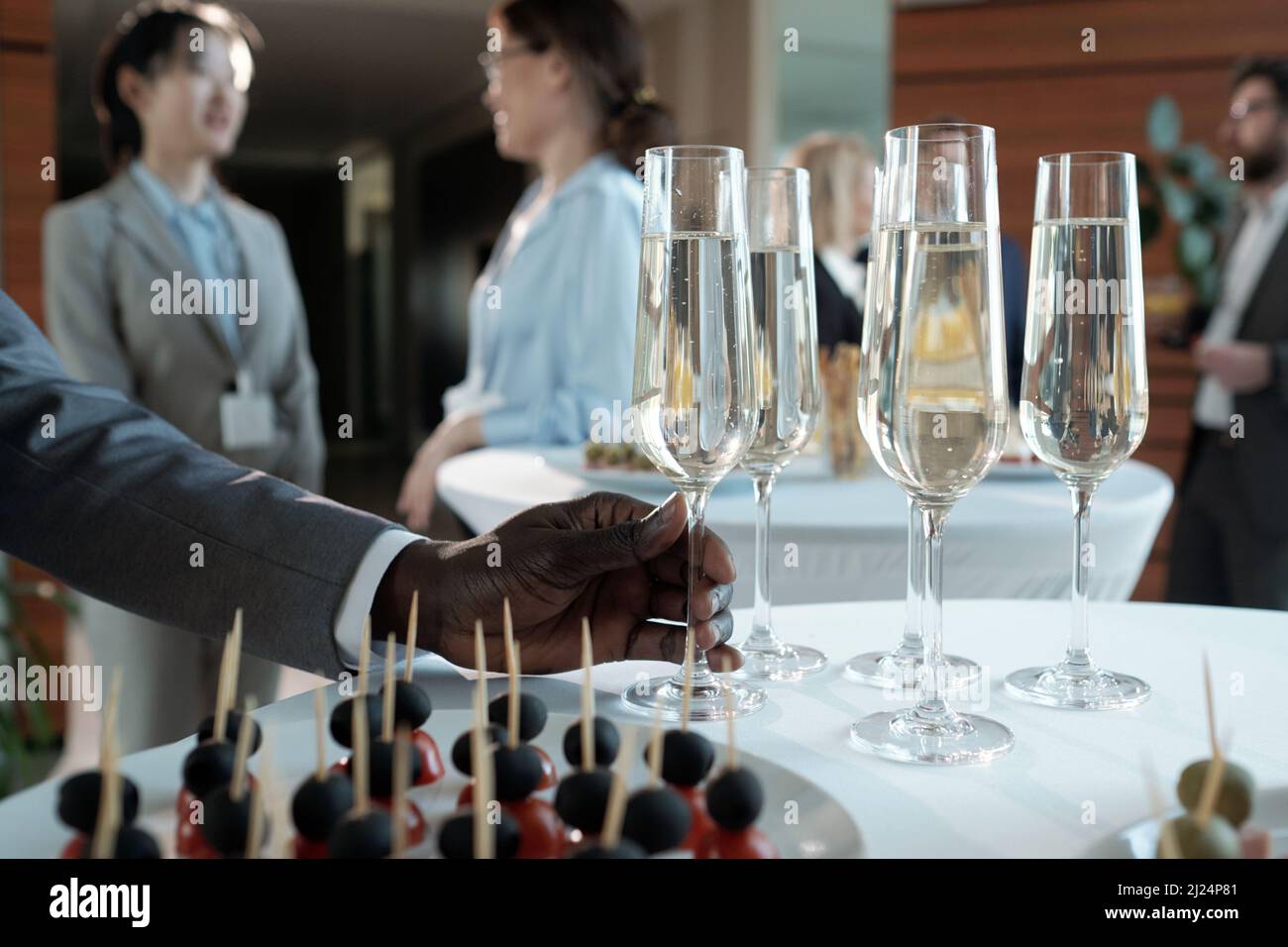 Hand of young African American businessman taking flute of champagne