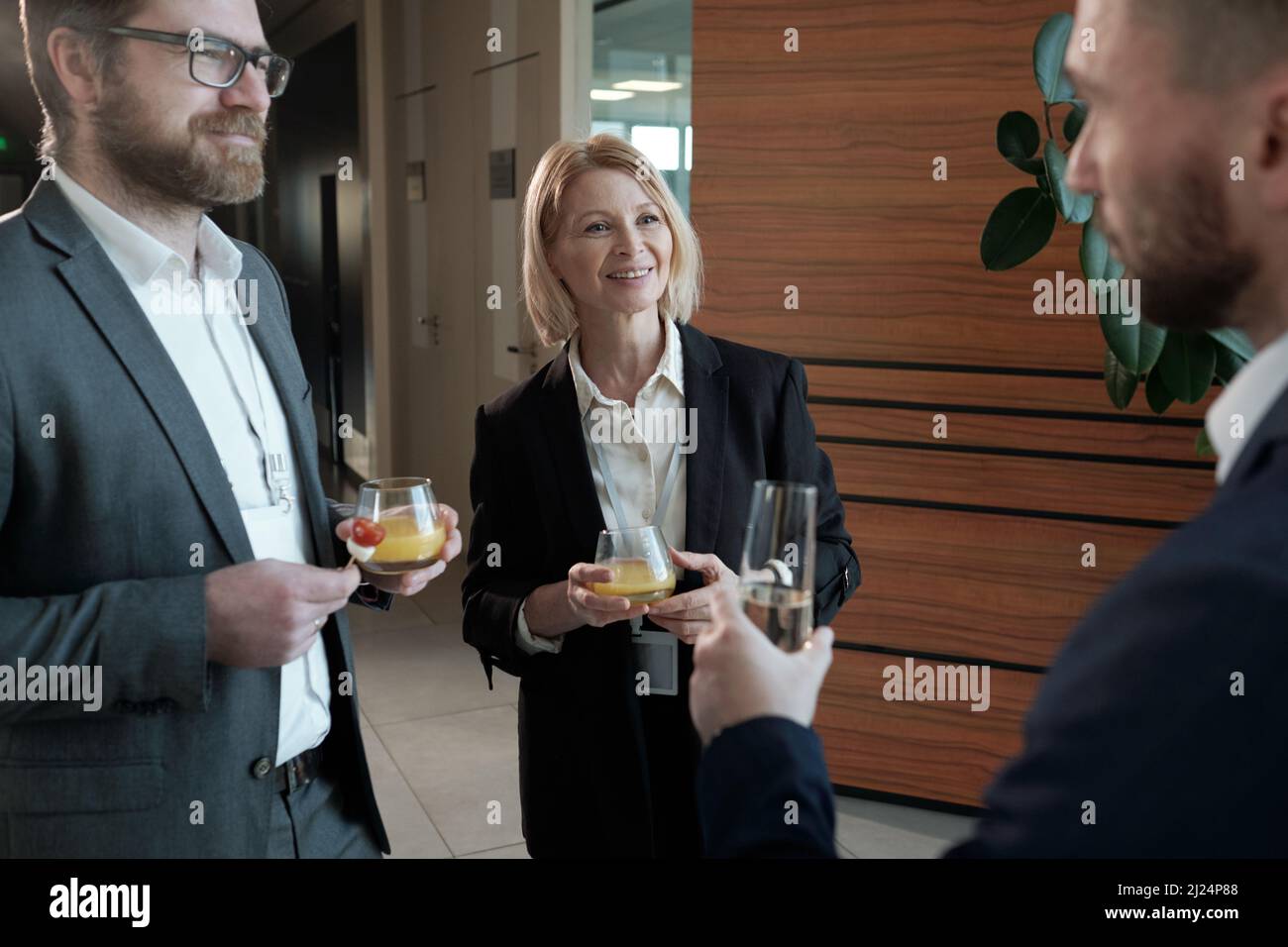 Group of contemporary entrepreneurs with juice looking at colleague