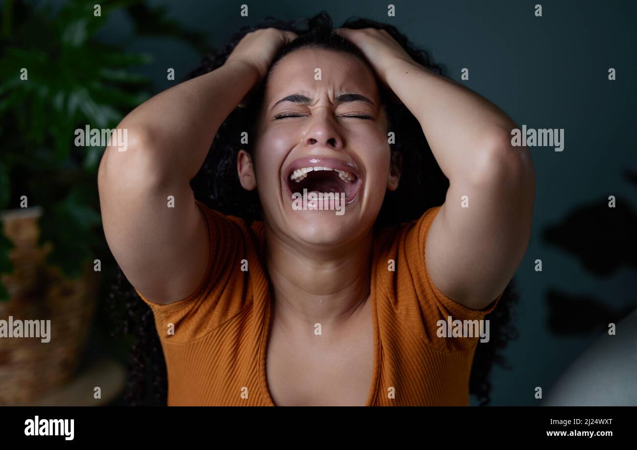 A broken heart makes life feel like its falling apart. Shot of a young woman feeling unhappy at home. Stock Photo
