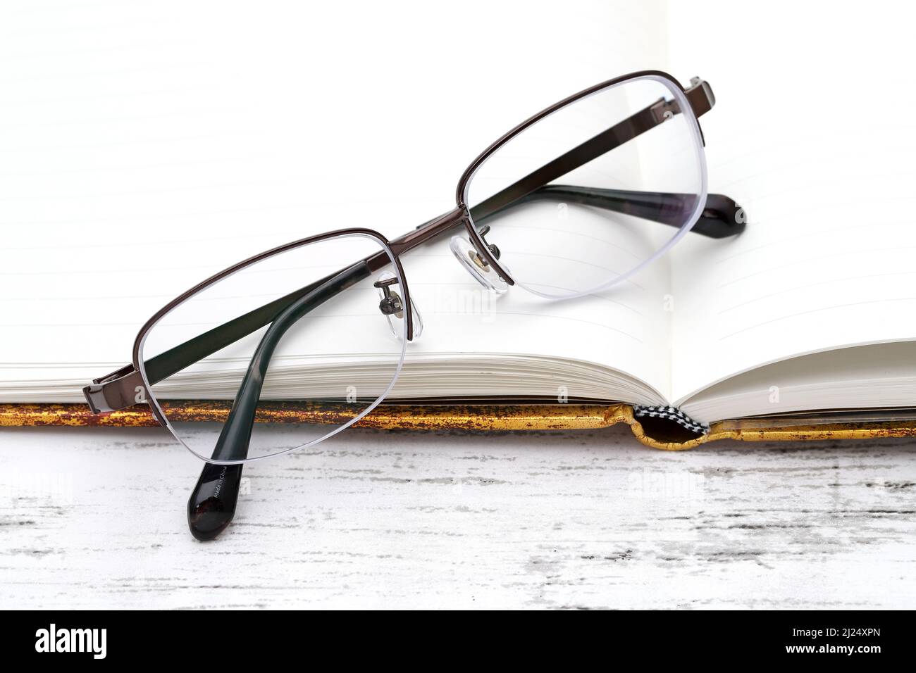 Stylish eyesight glasses and opened notebook on white wooden table Stock Photo