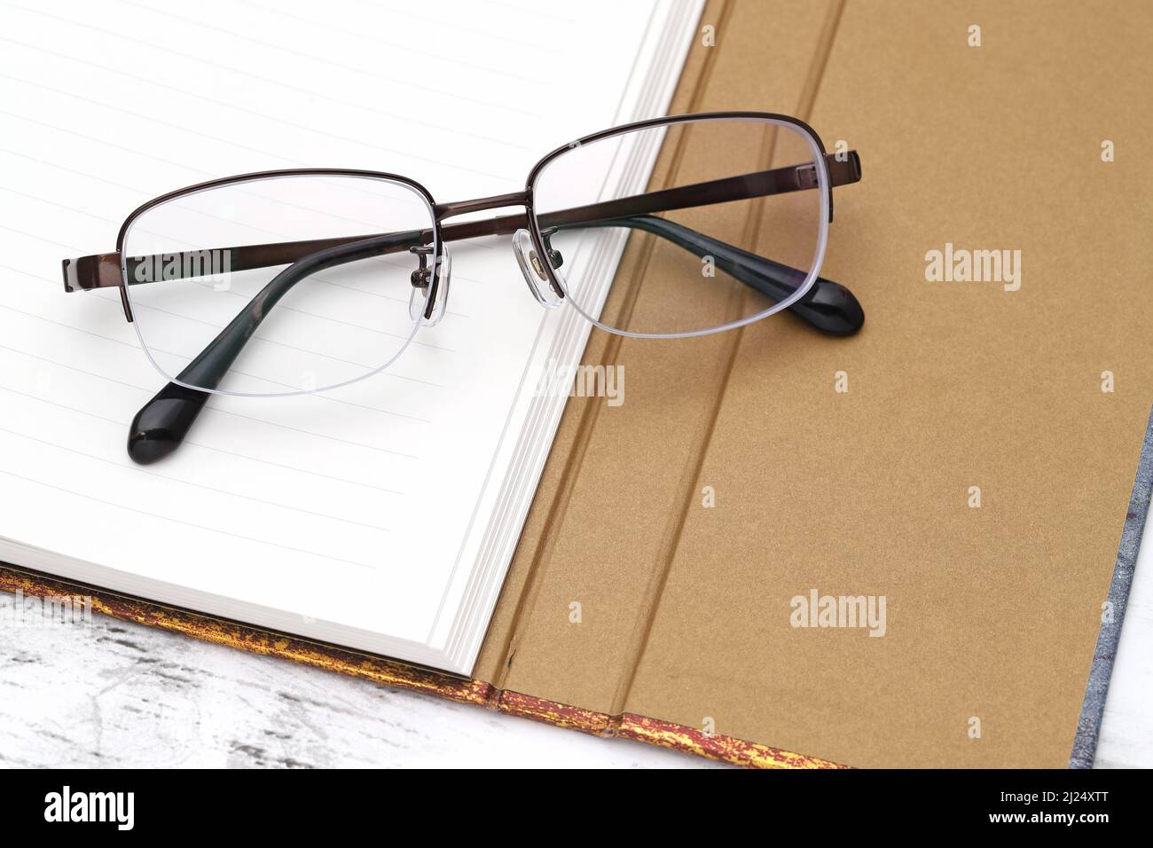 Stylish eyesight glasses and opened notebook on white wooden table Stock Photo