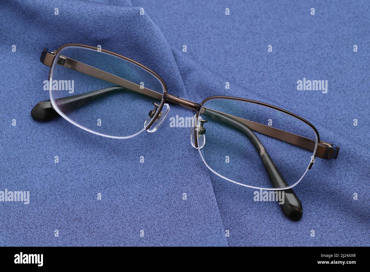 Stylish eyesight glasses and blue glass cleaning cloth backgrond Stock Photo