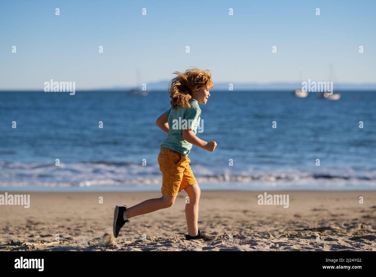 Kid running on beach. Happy child run in sea on summer vacation Stock