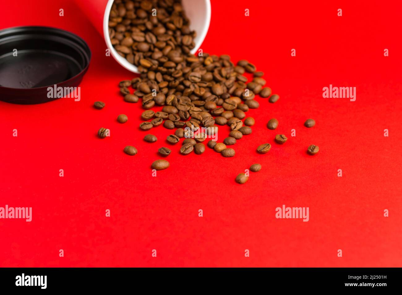 Takeaway red paper coffee cup with black cap on red background with ...
