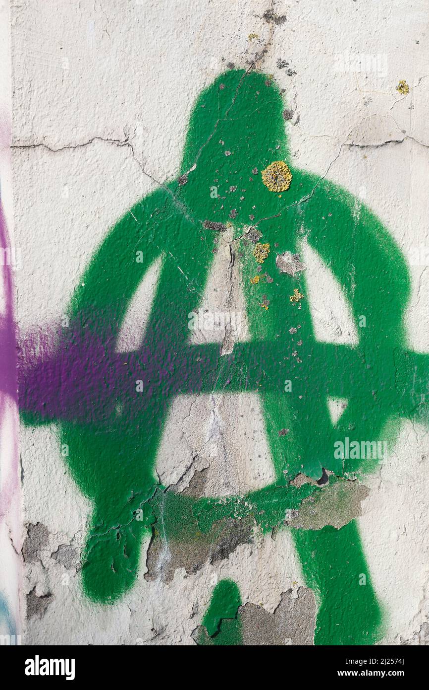 Green A for anarchy painted on white garden wall Stock Photo