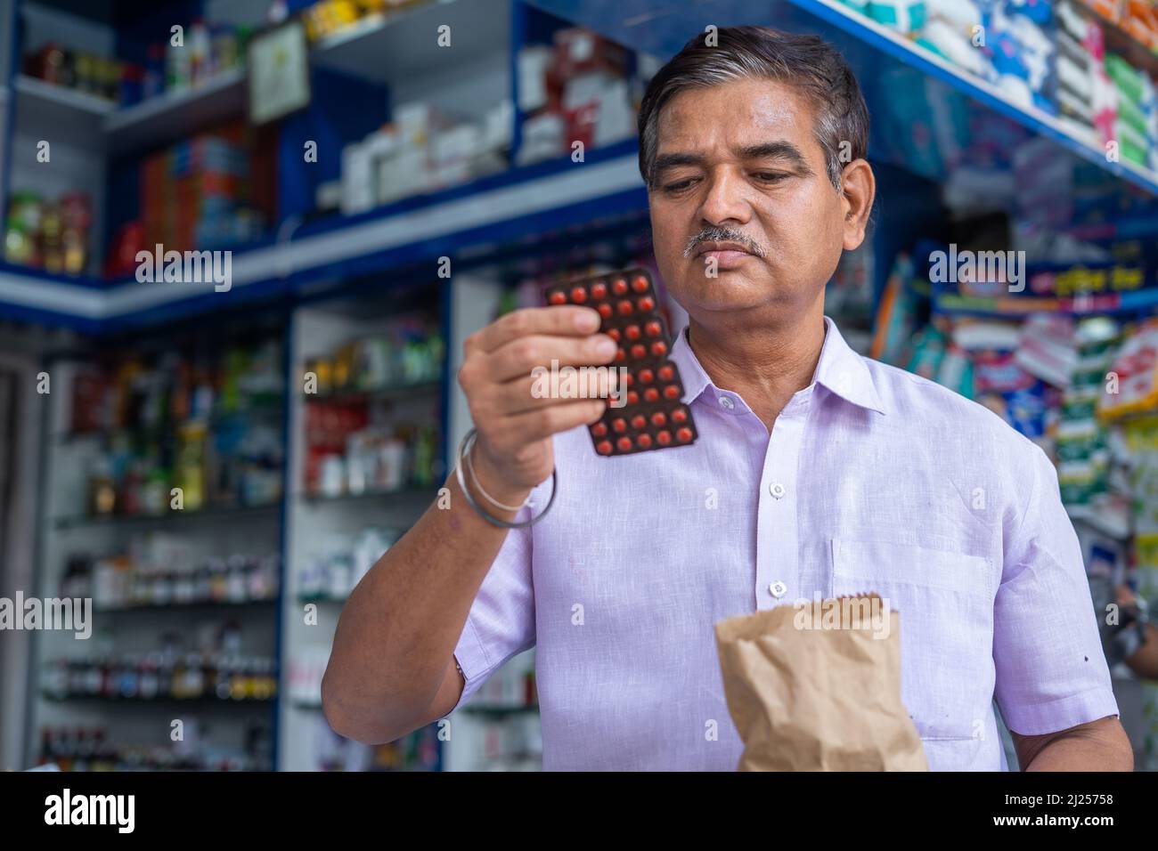 customer checking medicine price and expiry date at retail medical shop after purchasing - concept of shopping, consumer awareness, pharmacist and Stock Photo