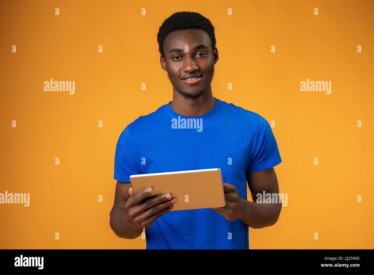 Smiling african guy using digital tablet over yellow background Stock Photo