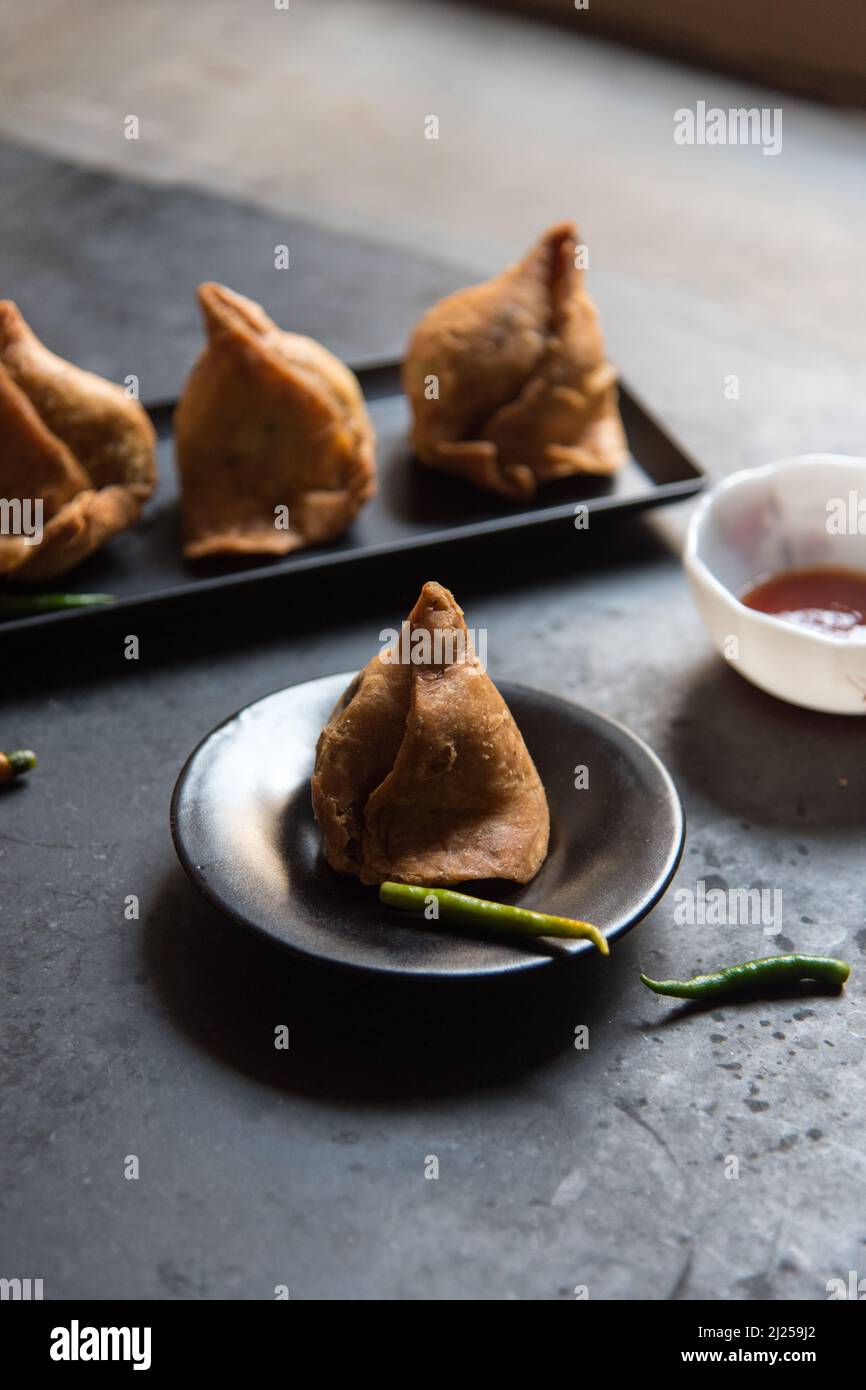 Indian snacks samosa or triangle shaped fried food on a dark background Stock Photo
