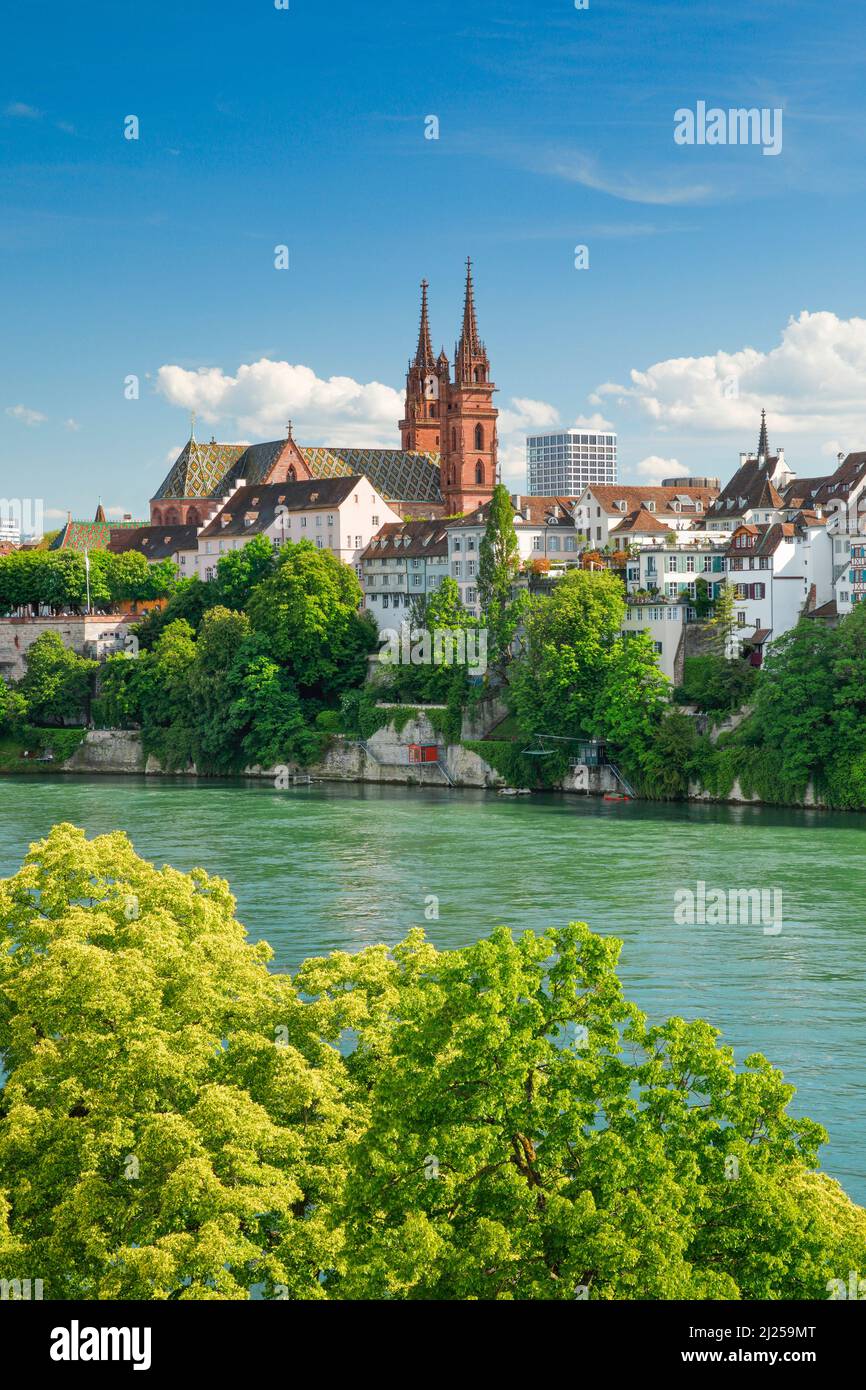 View of the Basel Minster in the middle of Basel's old town with the turquoise-colored river Rhine in the foreground. Switzerland Stock Photo