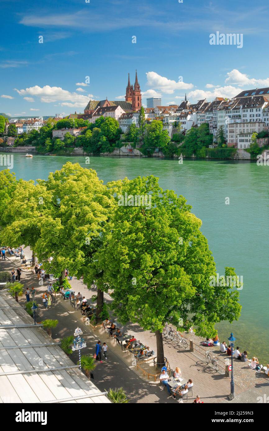 View of the Basel Minster in the middle of Basel's old town with the turquoise-colored river Rhine in the foreground. Switzerland Stock Photo