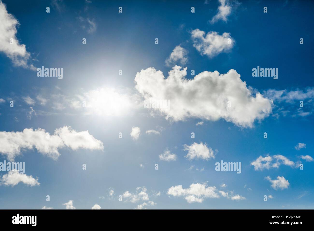 Sun backlights cumulus clouds in blue sky Stock Photo