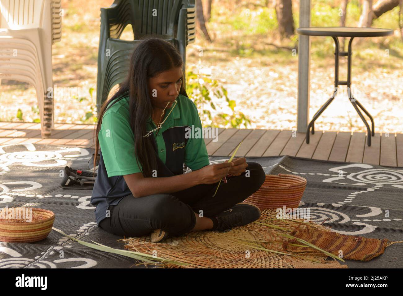 A young Aboriginal woman weaving a basket in Kakadu National Park