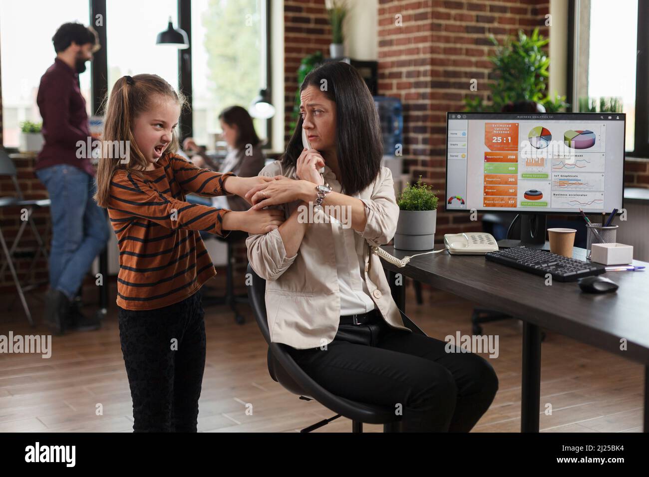 Working businesswoman irritated by annoying little girl while talking