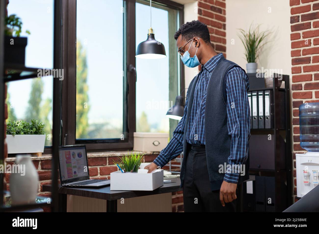 Startup employee wearing covid mask putting personal belongings in tray ...