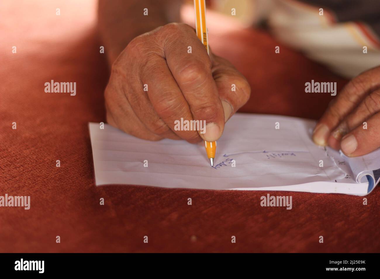 Closeup hands of an old man writing down and drawing a route on white page with traditional pen. Giving directions to a lost man. Taking notes. Stock Photo