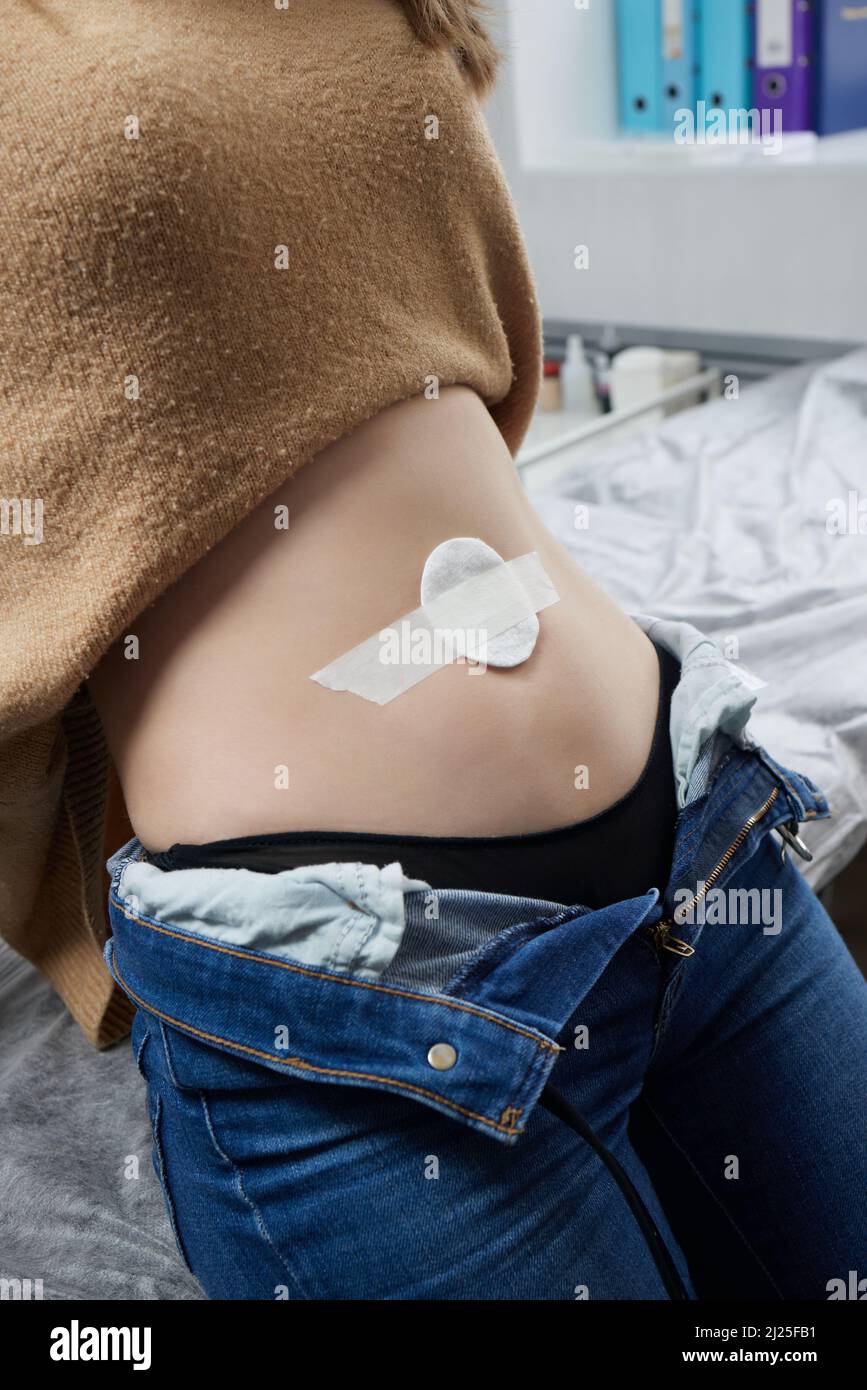 Close up of skin held in piercing tool as needle is ready to go in to