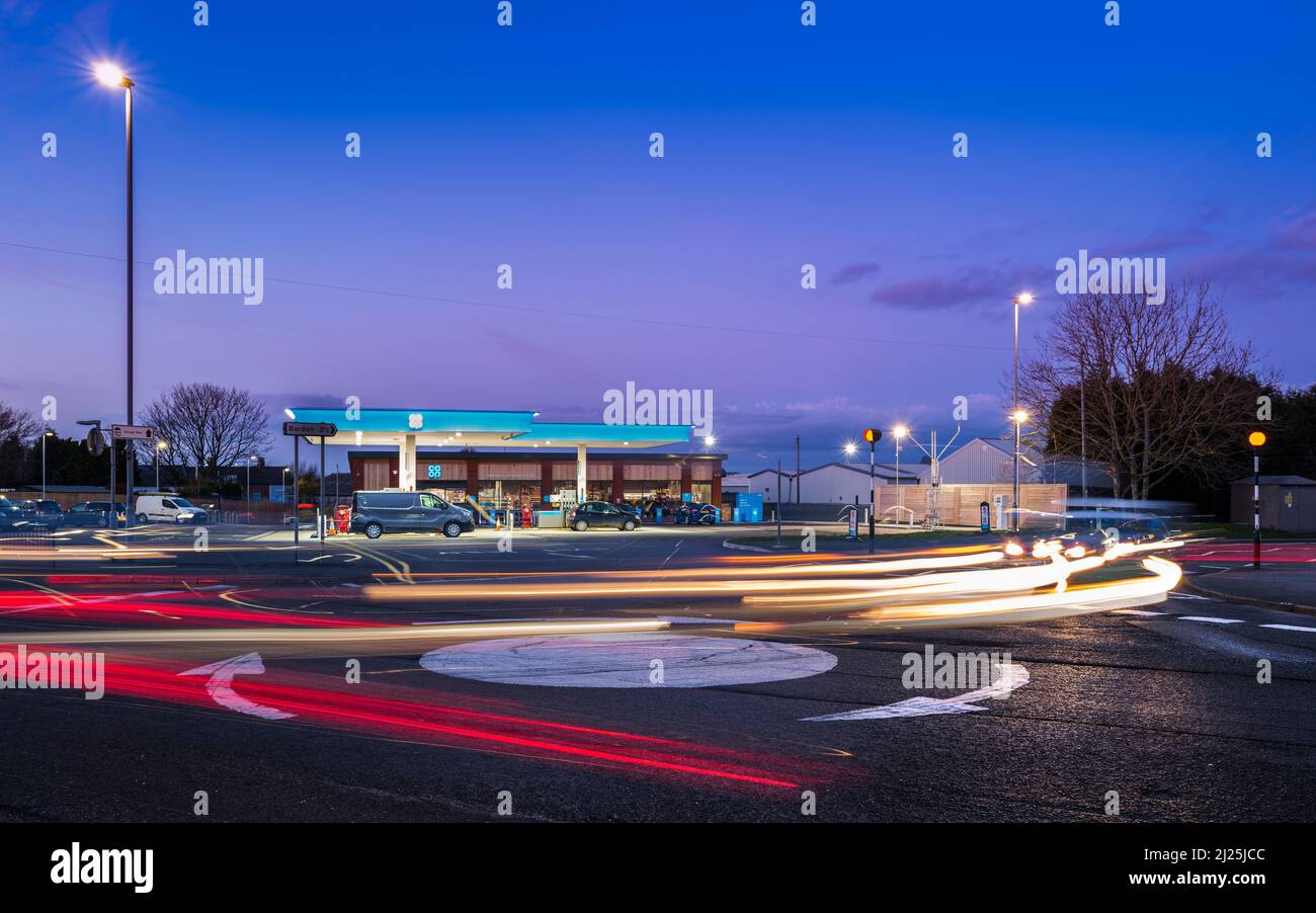 Rush hour traffic rounds a roundabout in front of a Co-op petrol station. Stock Photo