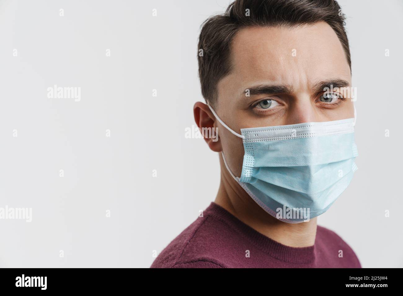 Young brunette man in face mask posing and looking at camera isolated ...