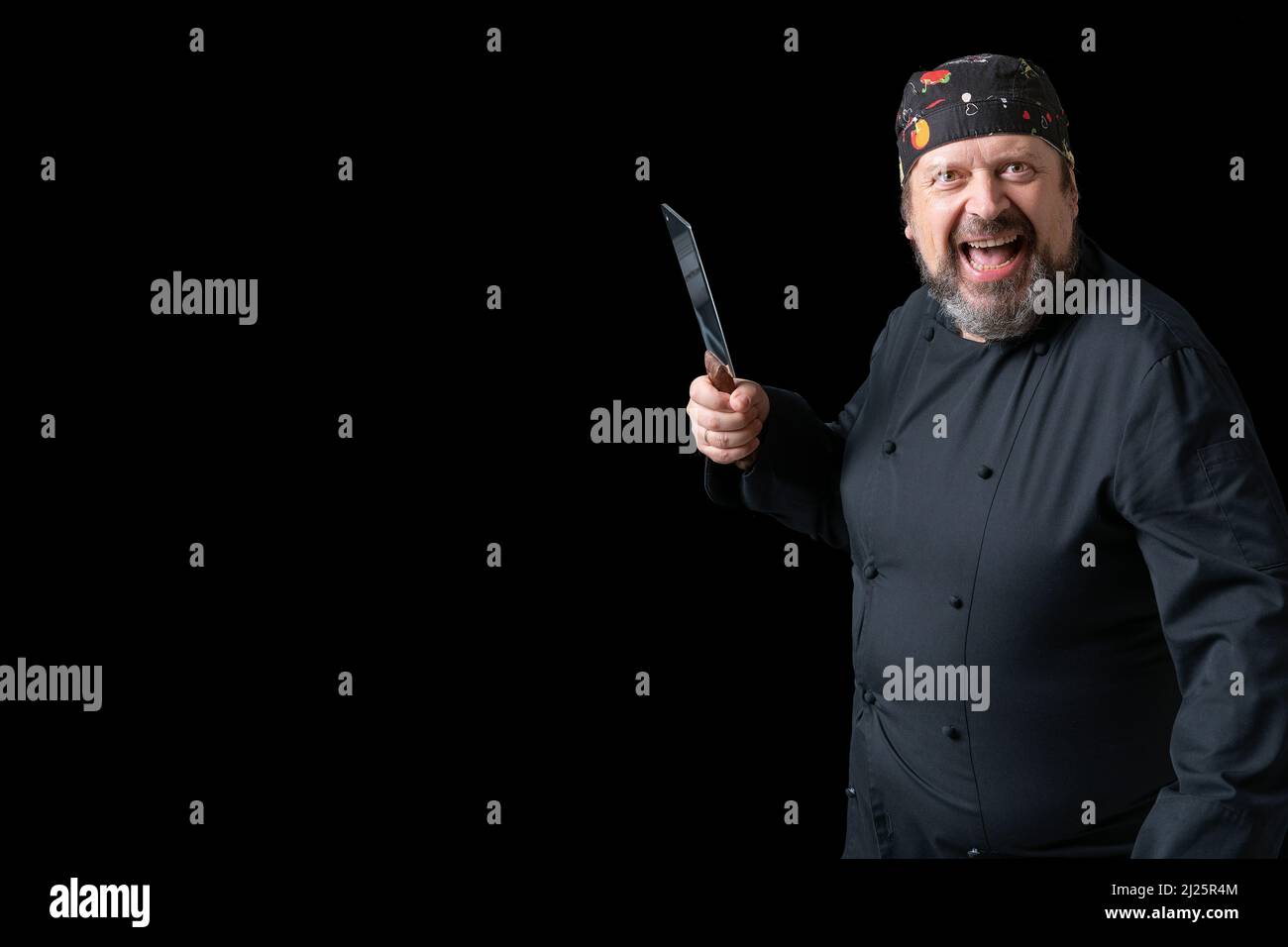 Portrait of cook with knife in hand with black background and copy space on the left side. Expressions of concept. Stock Photo