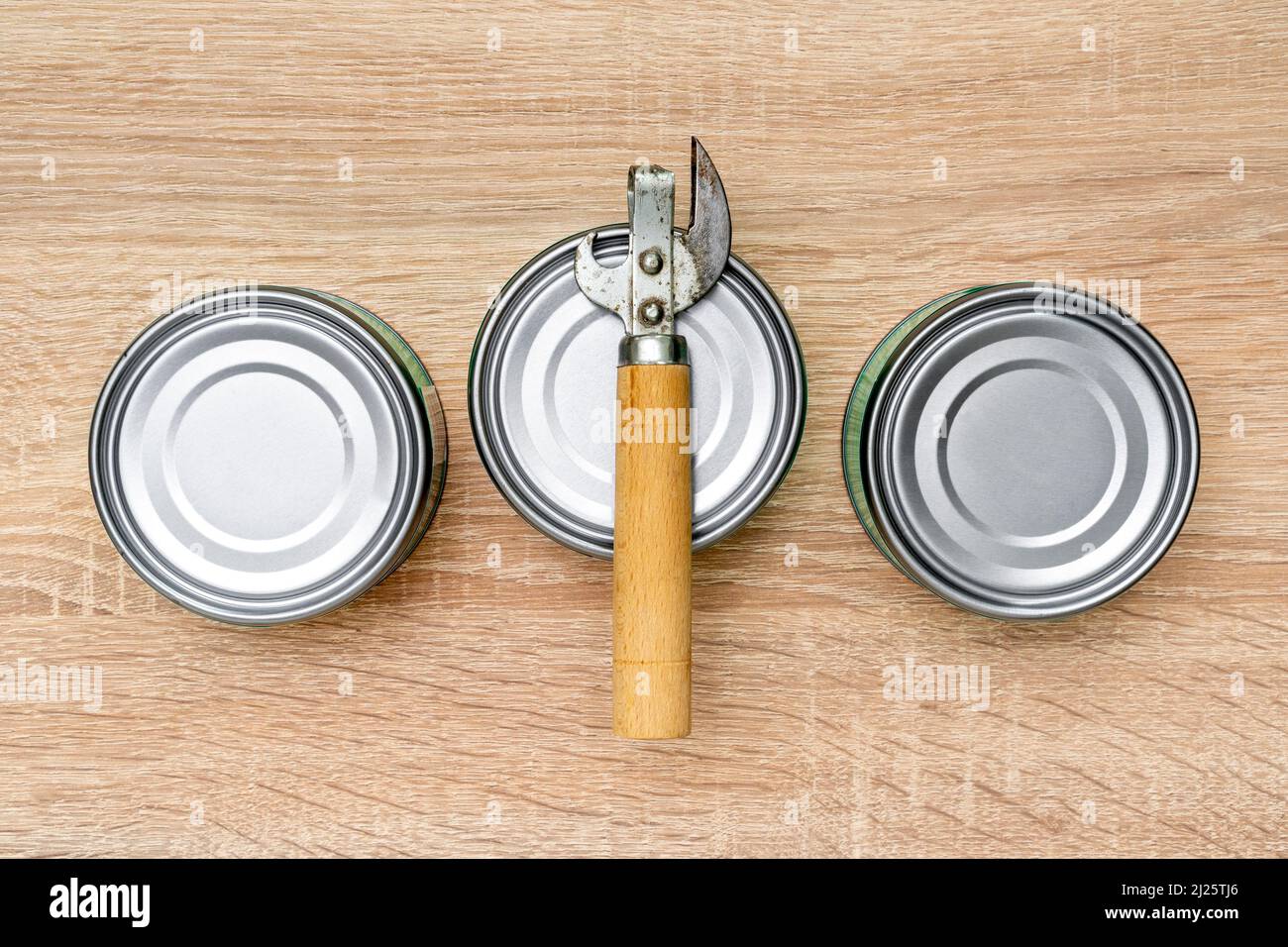 https://c8.alamy.com/comp/2J25TJ6/old-can-opener-and-metal-cans-on-the-table-in-the-kitchen-canned-food-healthy-eating-and-lifestyle-2J25TJ6.jpg