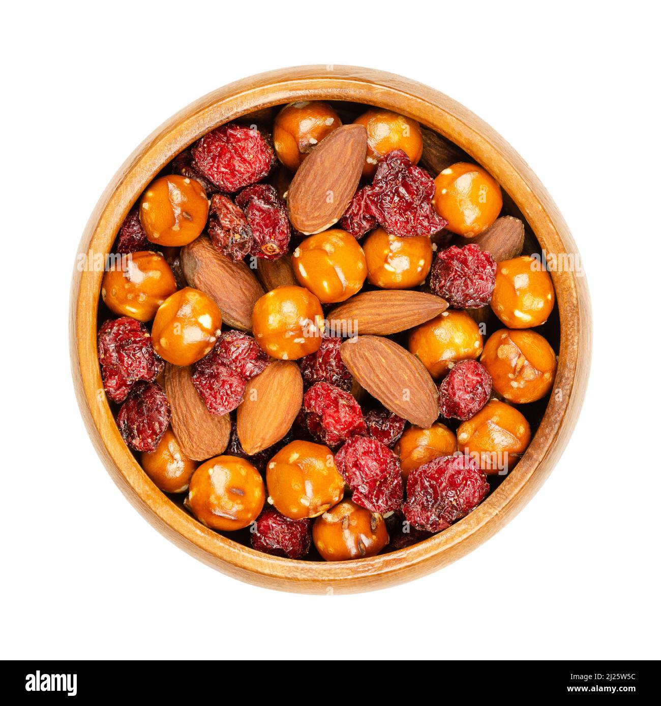 Crunchy mix, in a wooden bowl. Crunchy mix of salted pretzel balls, roasted almonds and baked cranberries. Close-up, from above. Stock Photo