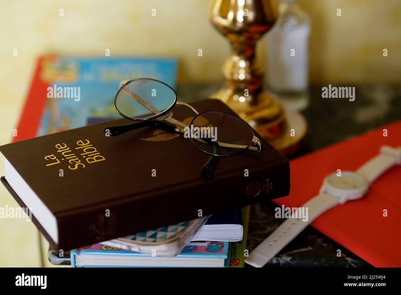 Holy Bible book on a bedside table beside a bed in a bedroom. Religion