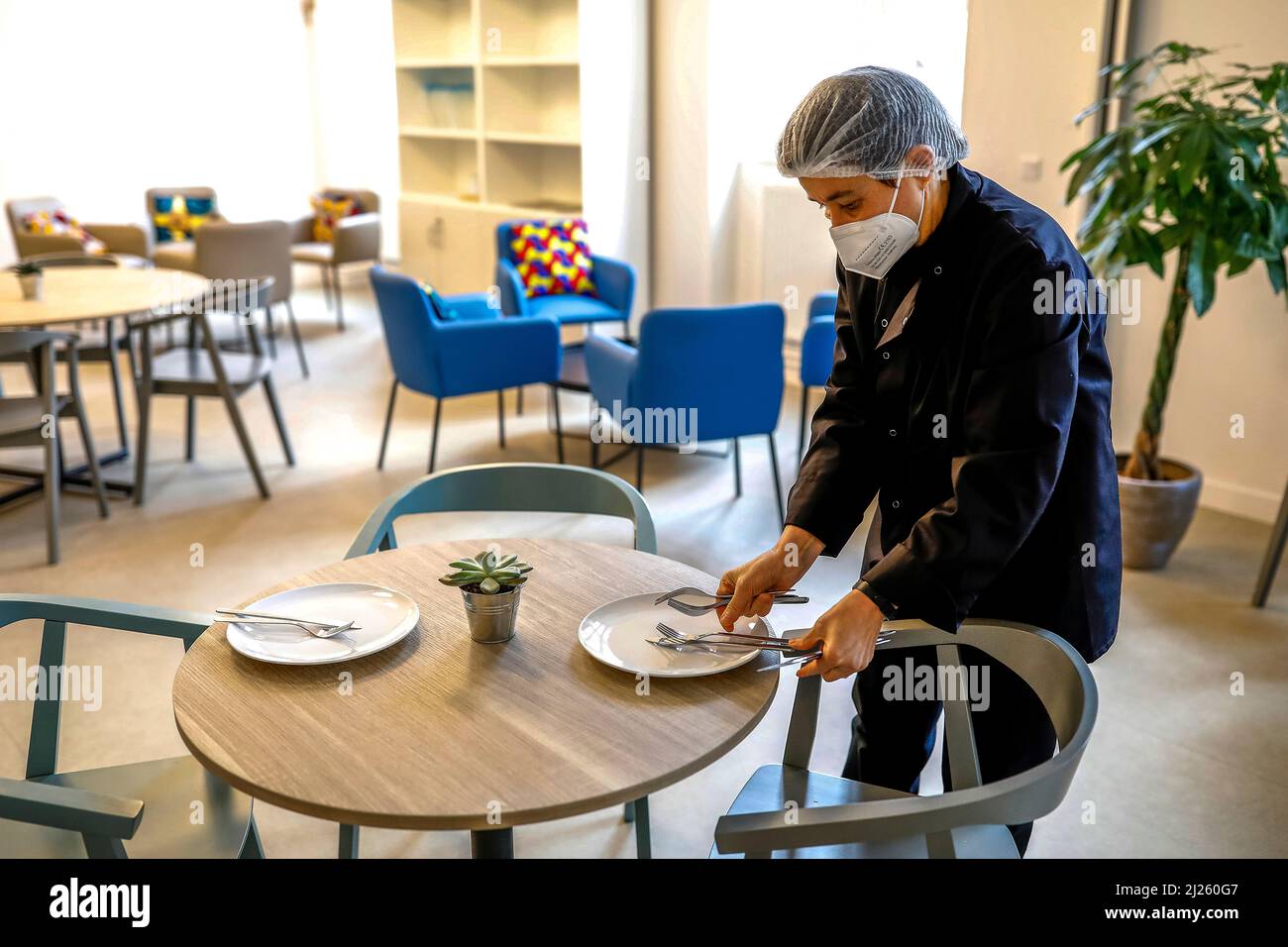 Nun laying a table for lunch at la Maison Bakhita, a center for migrants set up by the catholic diocese of Paris, France Stock Photo