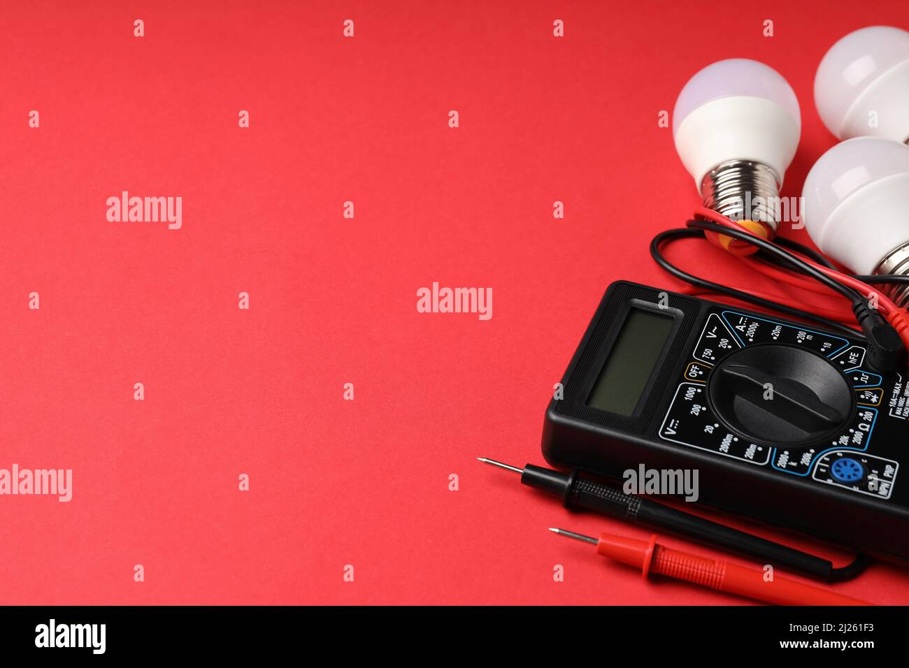 Multimeter and energy saving bulbs on red background Stock Photo